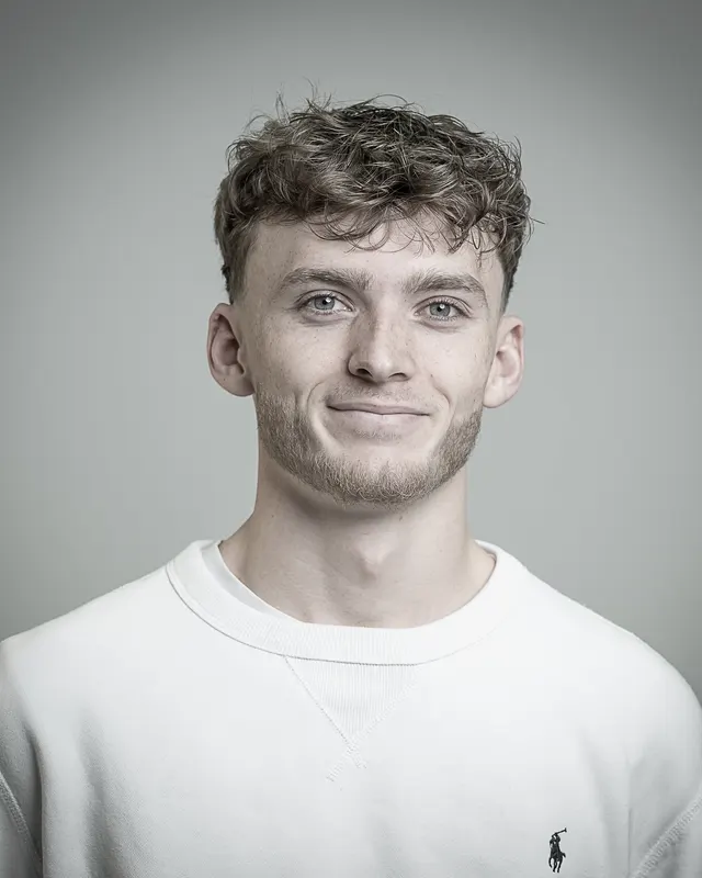 Portrait d'Aurélien Dochy, souriant, en pull blanc